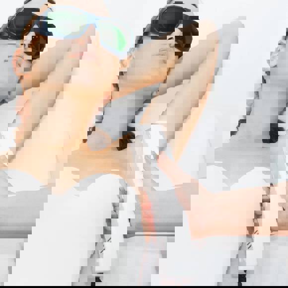 Portrait of woman wearing protective glasses during underarm hair removal