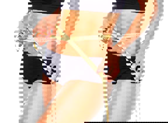 Woman measuring her slim waist after body contouring treatment