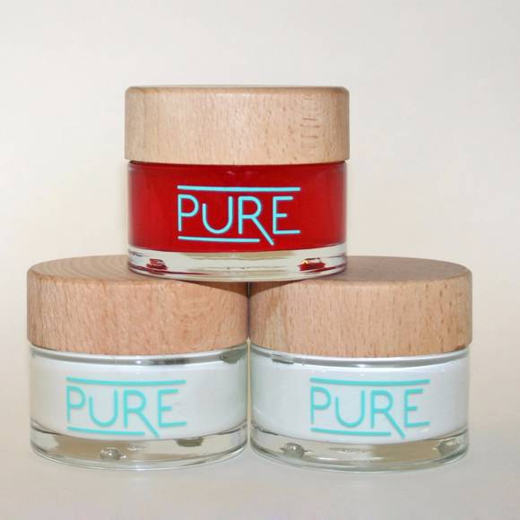 Three minimalist cosmetic jars labeled PURE, featuring wooden lids and clean modern design
